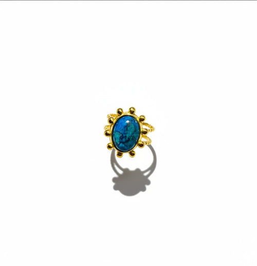 Bague Majoa Azura ajustable en acier inoxydable doré avec une pierre bleue ovale sertie de perles métalliques.