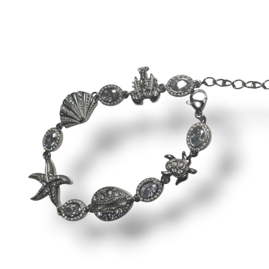 Bracelet Majoa argenté en acier inoxydable avec motifs étoile de mer, tortue, coquillage et zircons scintillants.