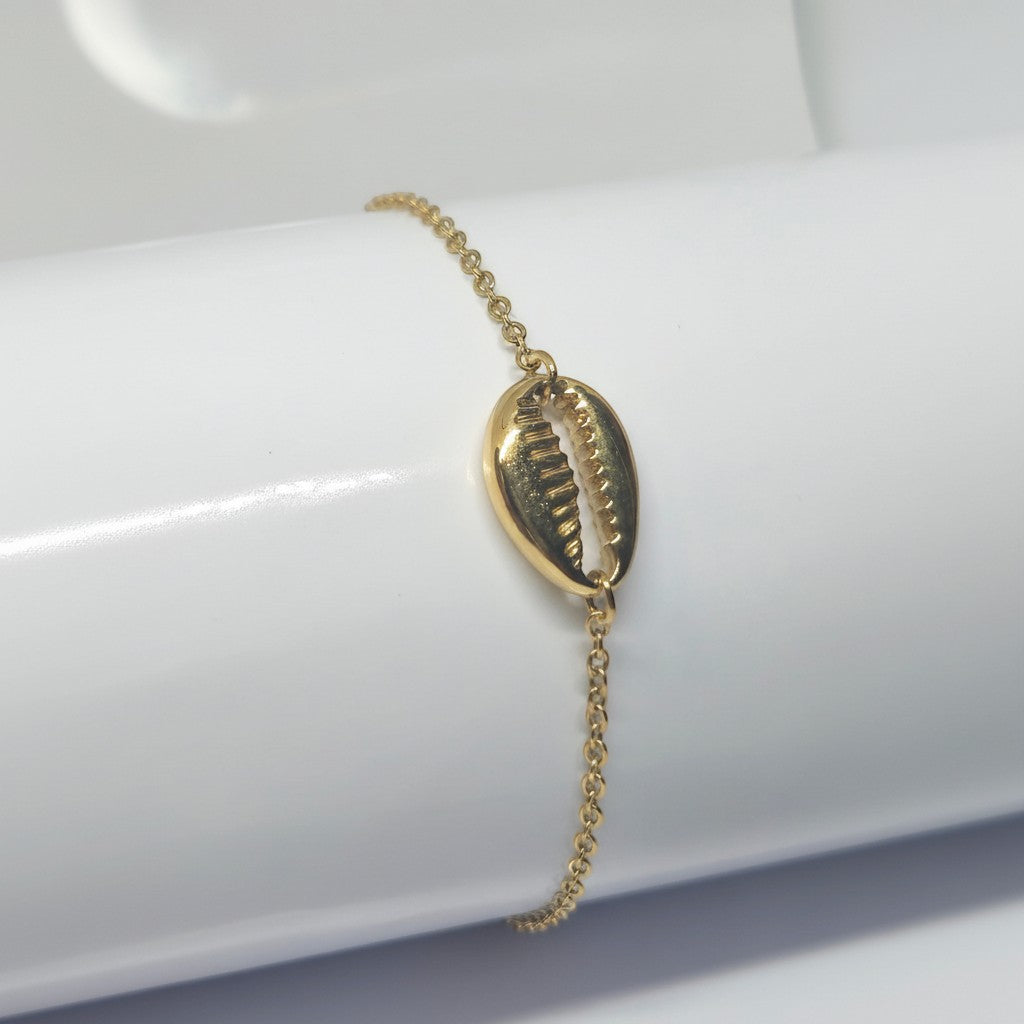 Majoa gold stainless steel bracelet with a cowrie shell charm. Delicate chain, water-resistant, hypoallergenic.