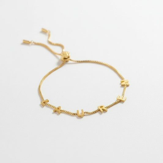 Majoa gold plated 18K stainless steel adjustable bracelet with personalized letters spelling 'LAURE'.